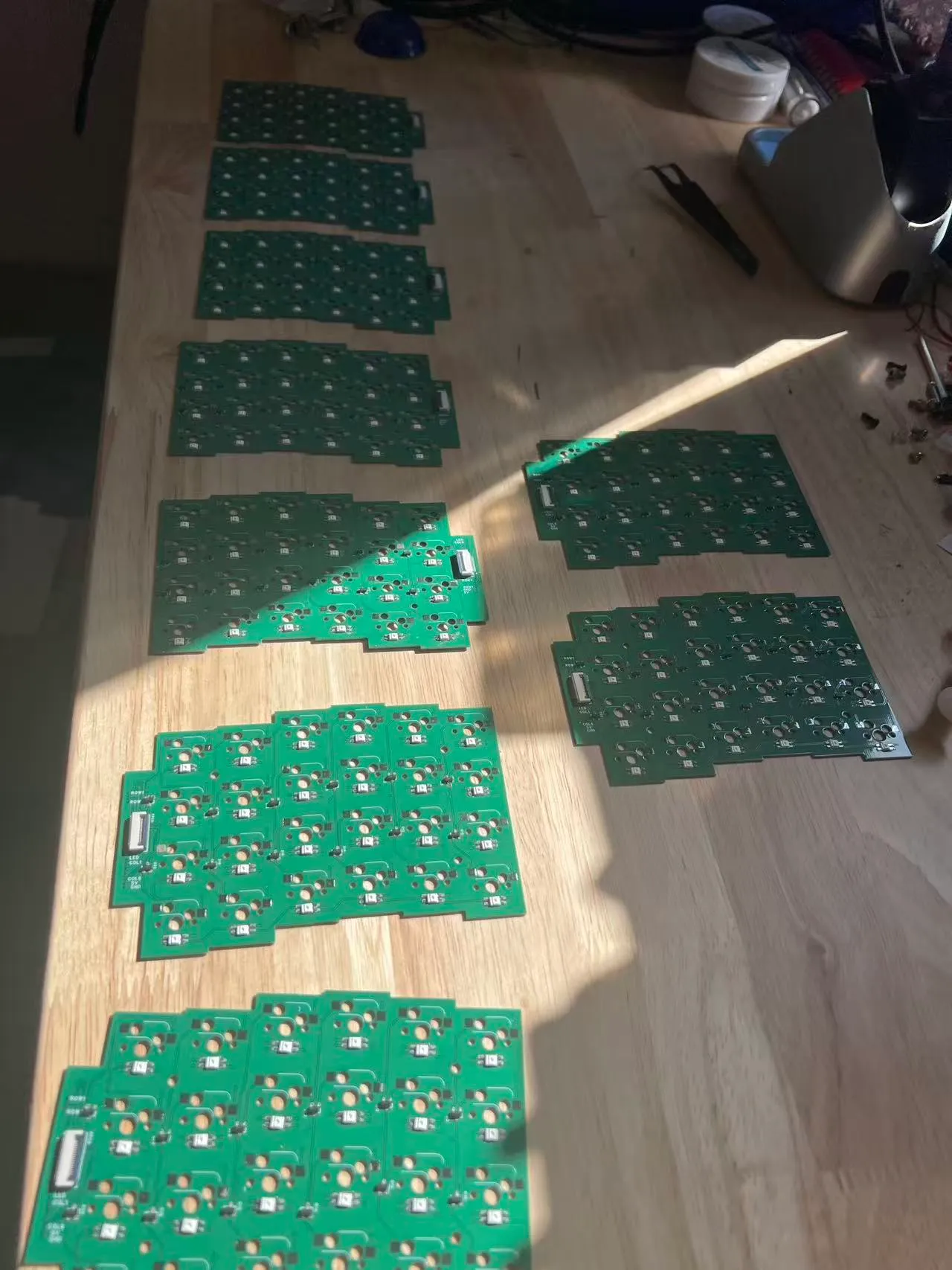 Rows of green PCBs laid out on a wooden floor