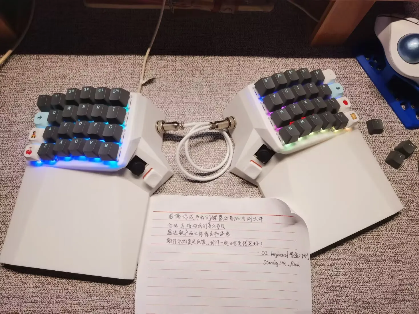 White OS Keyboard with RGB lighting and a handwritten thank-you note