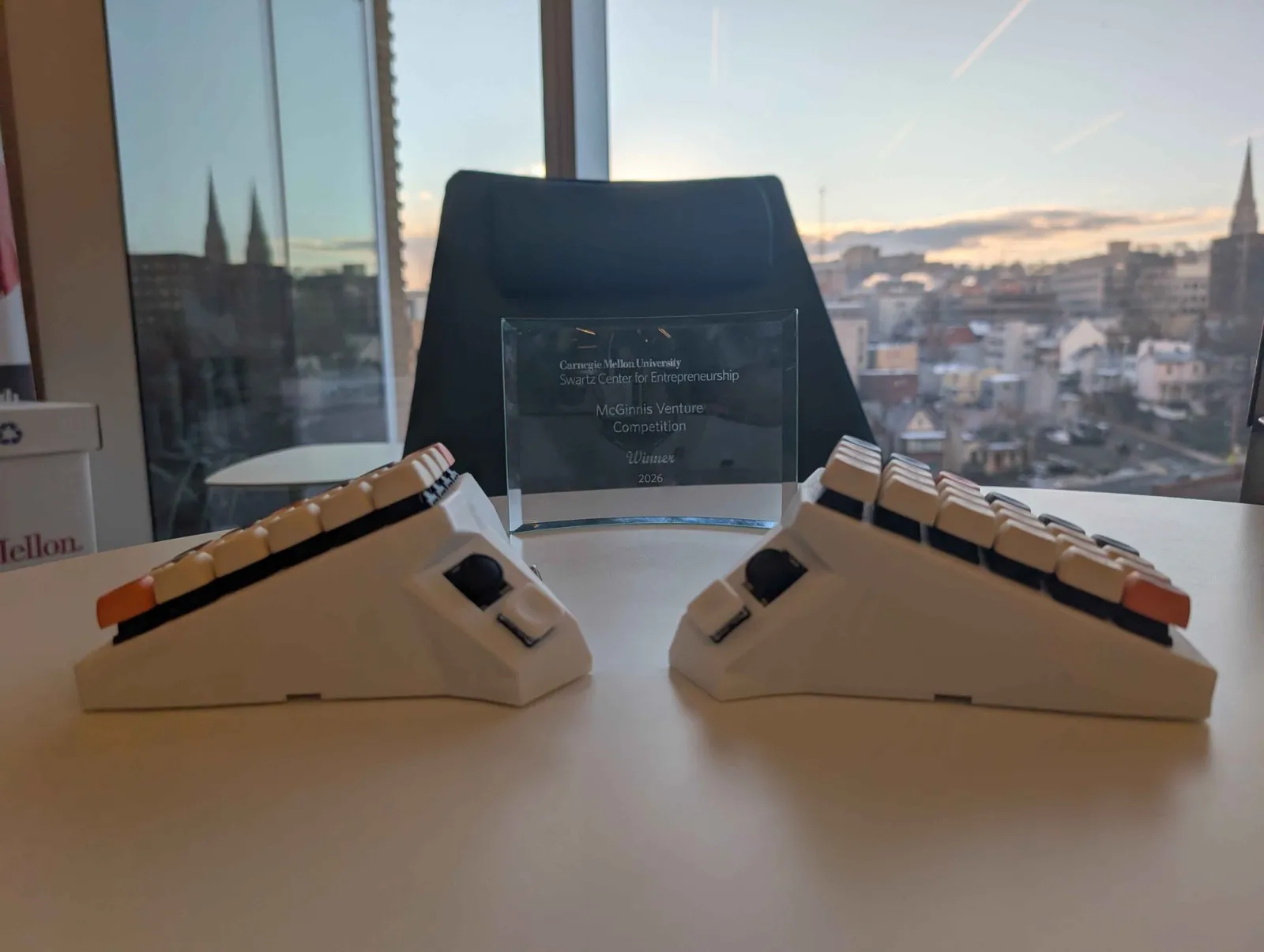 OS Keyboard beside a 2026 McGinnis Venture Competition winner award
